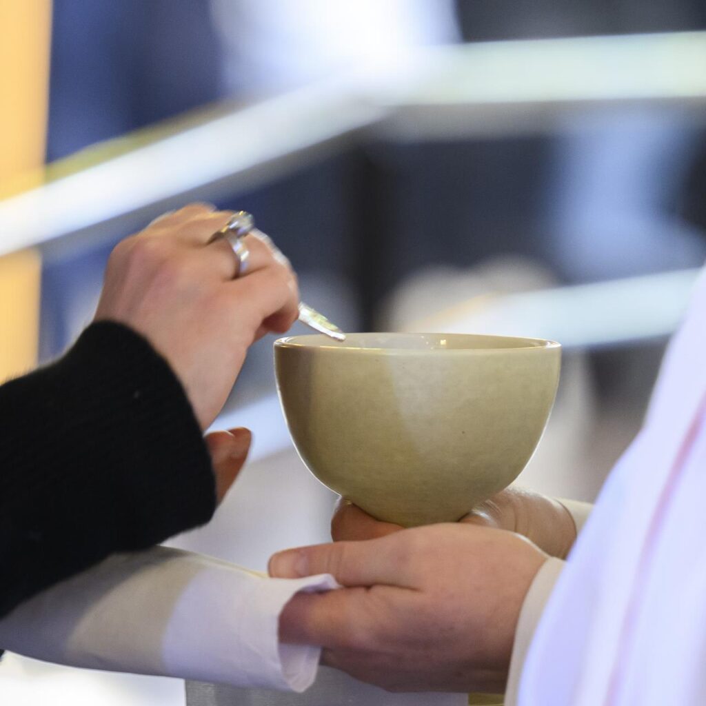 Händer av en person som håller en bägare och en annan som välsignar den